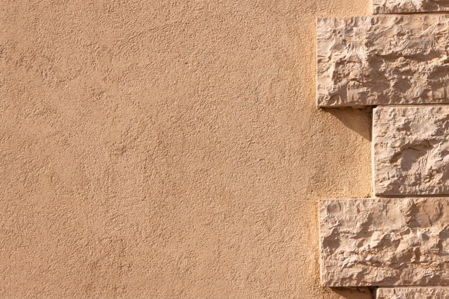 Warm tan stucco wall meeting a corner of rough-cut stone blocks