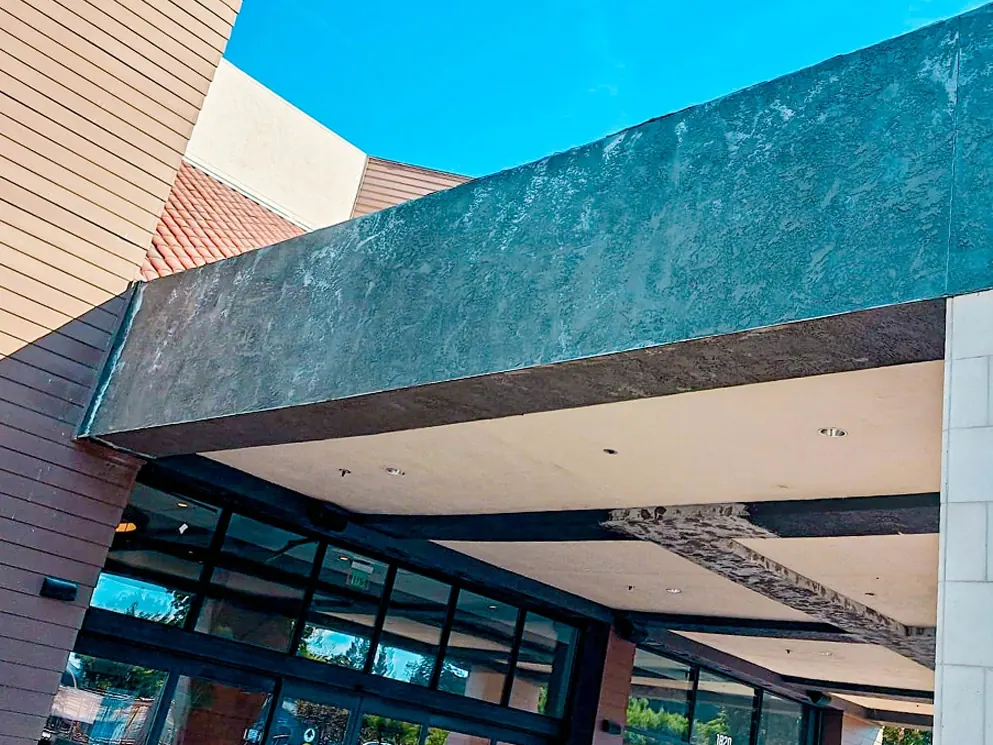 Weathered stucco beam fascia above a commercial building entrance