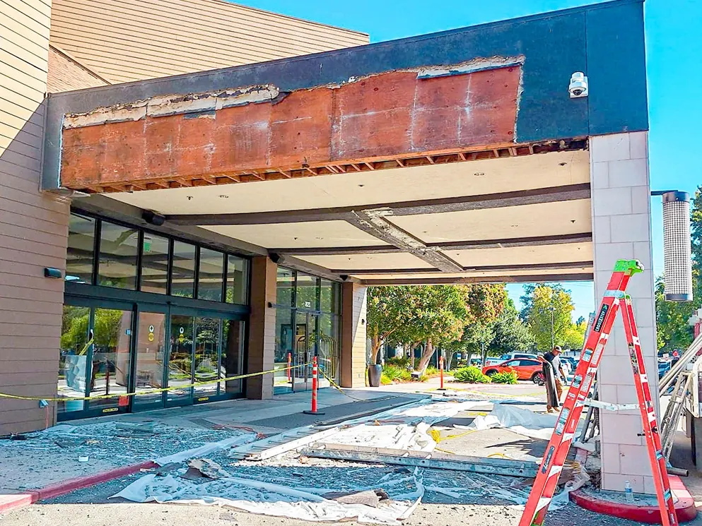 Commercial entry canopy stripped of stucco with the entrance protected below