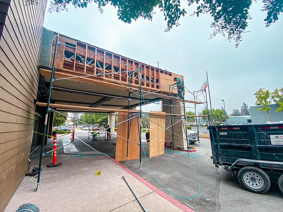 Commercial entry canopy opened to framing with scaffolding and plywood shoring in place