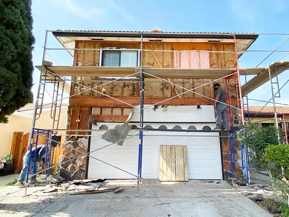 Two story San Jose home scaffolded and opened to the framing during an exterior remodel