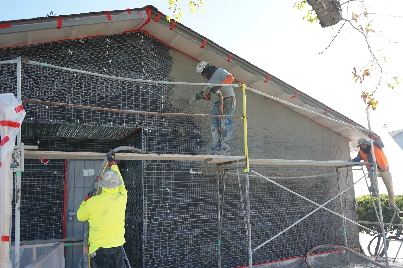 Crew spraying the scratch coat over metal lath on a Mayfair apartment gable wall