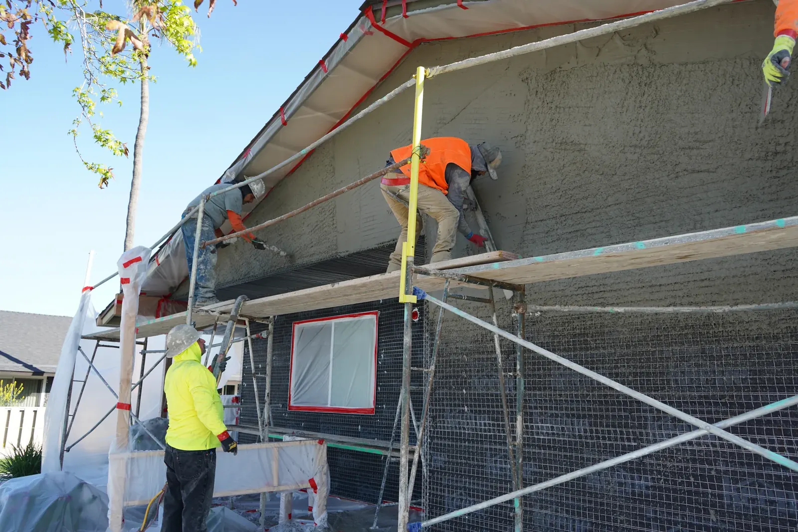 Crew troweling the scratch coat above a masked window on a Mayfair apartment building