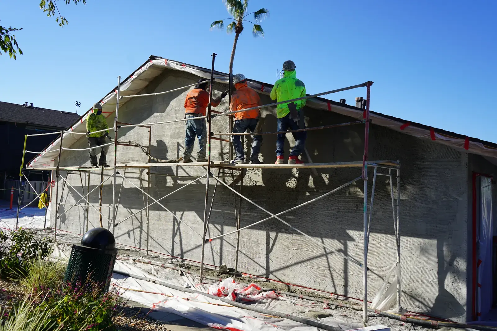 Four plasterers applying the brown coat from scaffolding on a Mayfair apartment gable