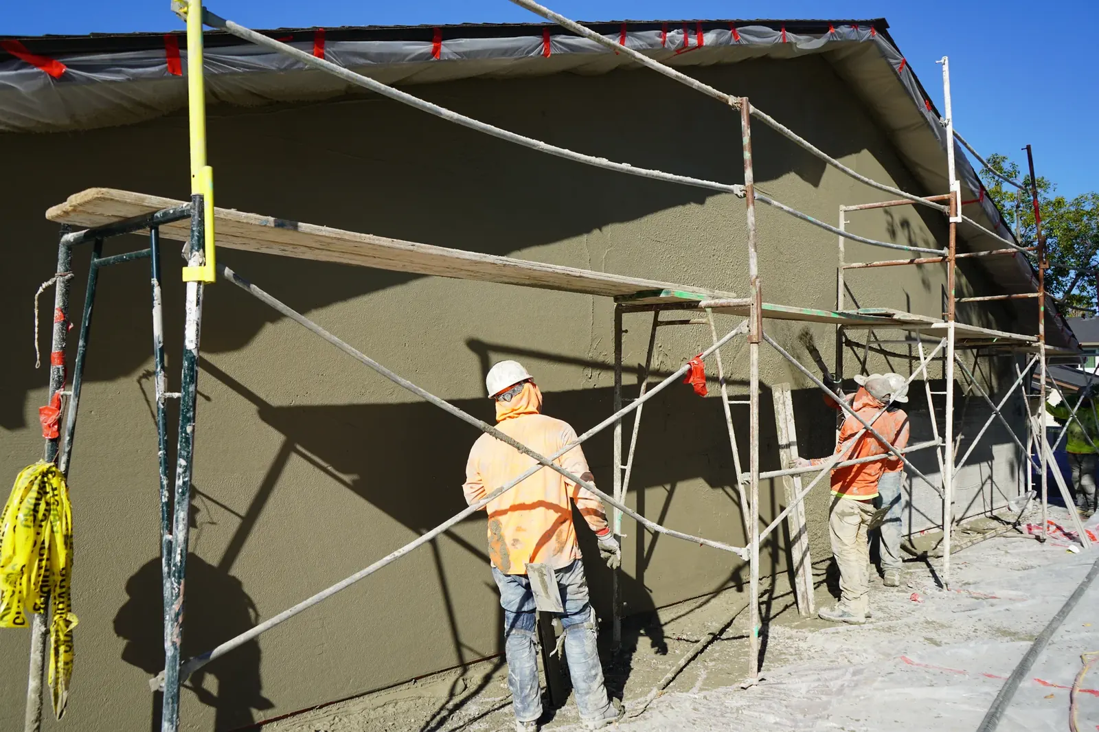 Plasterers leveling the brown coat along an apartment wall