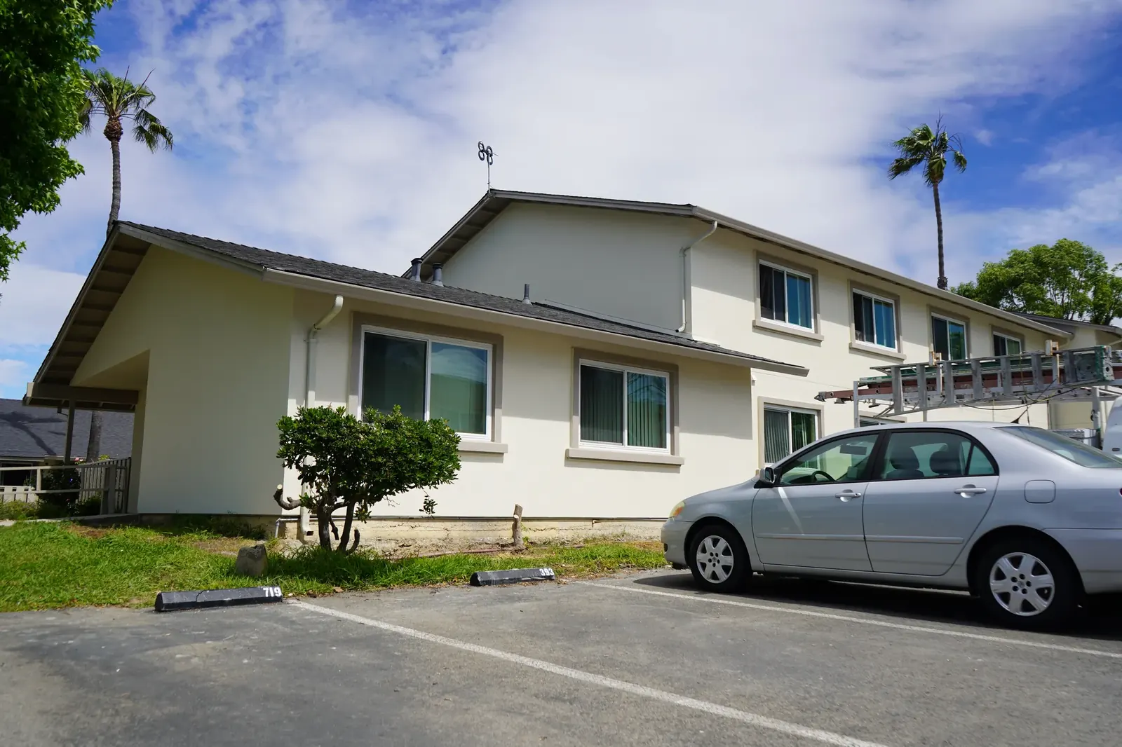 Finished Mayfair apartment building with cream stucco and trimmed windows beside parking