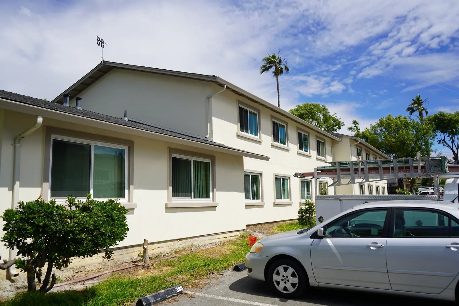 Finished two-story apartment elevation with cream stucco facing the parking lot
