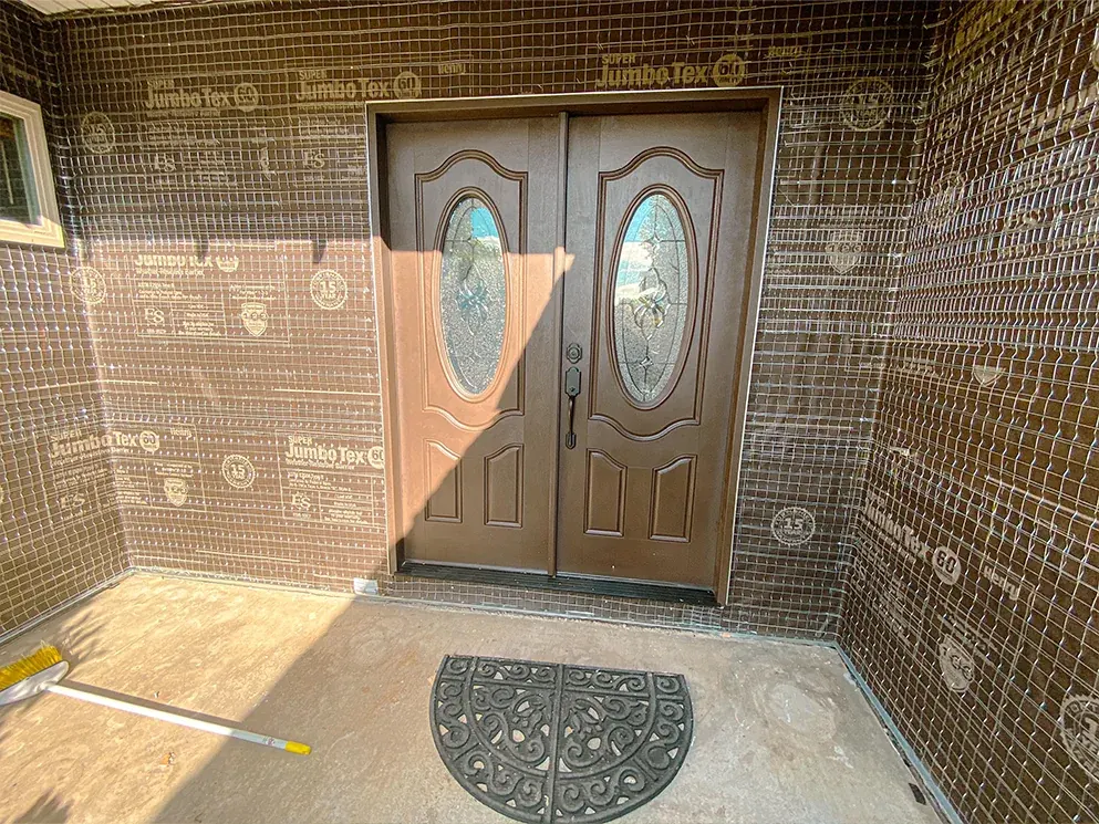 Front entry doors framed by new building paper and lath