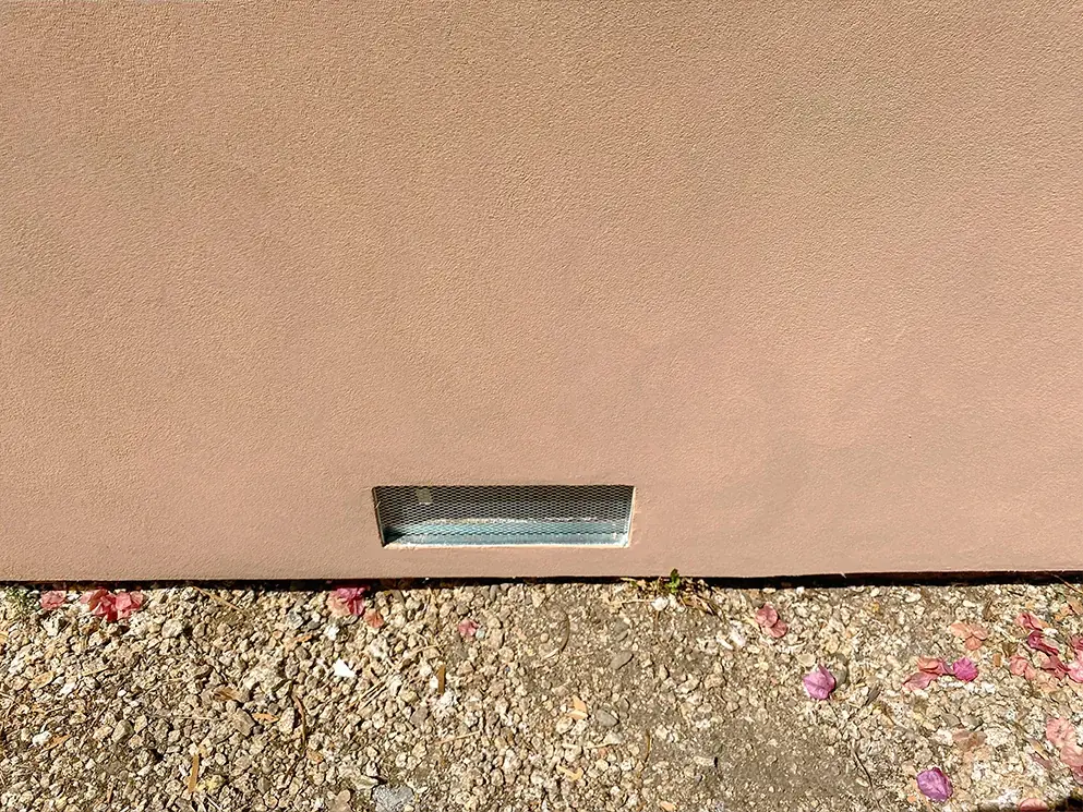 Close view of the acrylic smooth finish and foundation vent at the base of the wall