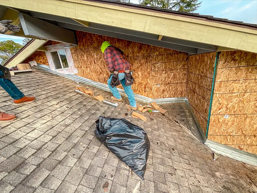 Crew installing flashing along the base of the new sheathing on the roof