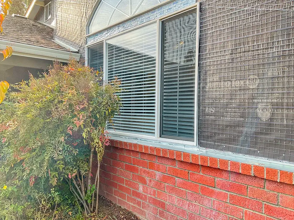 Building paper and metal lath beside the arched window above the brick base
