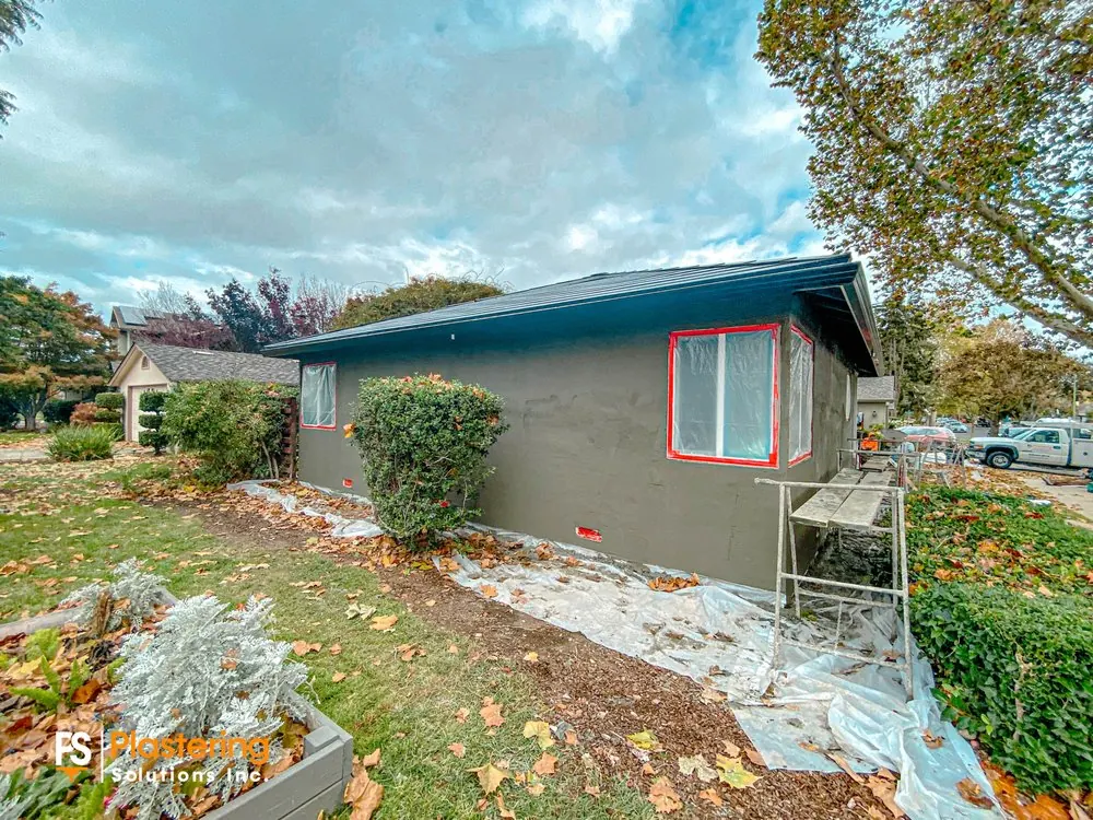 Home side with windows masked and the scratch coat applied, landscaping protected