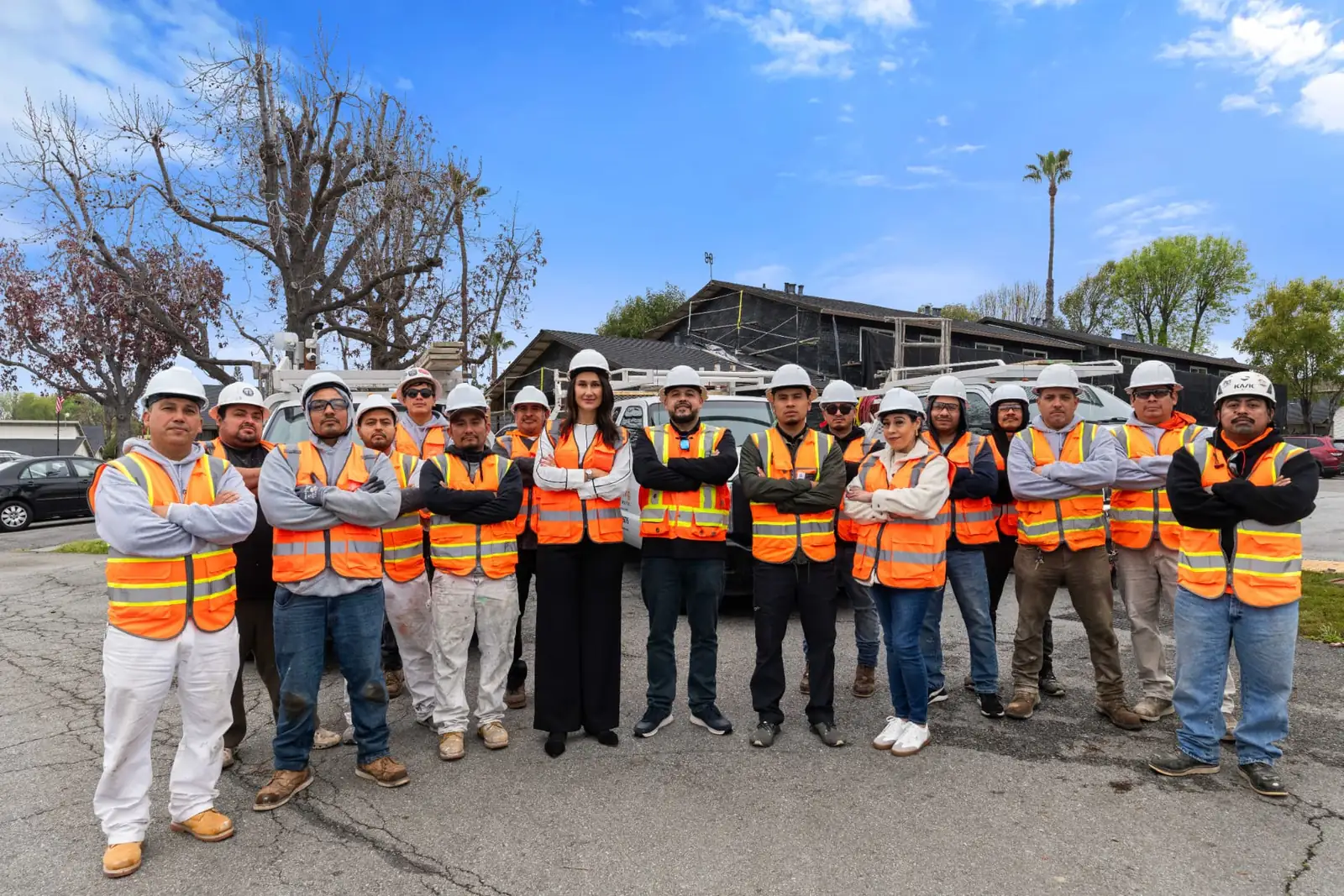 The Plastering Solutions Inc crew in white hard hats and orange safety vests standing together on a jobsite street